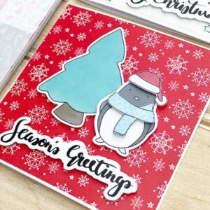 Cute handmade christmas card with penguin in a santa hat and scarf and christmas tree