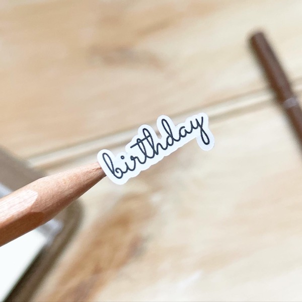 cute birthday text scripty sticker shown close up on a pencil tip
