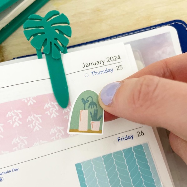 Plant sticker being placed on the page of a planner