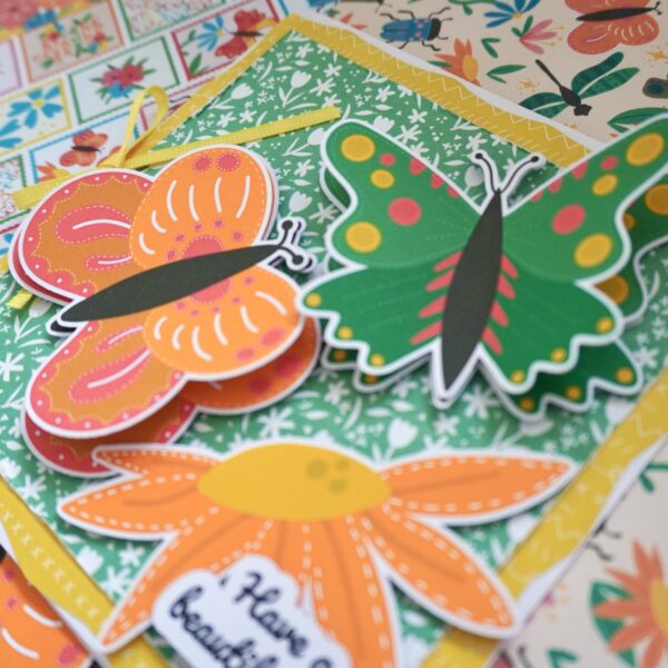 Butterfly ephemera – handmade card using cardmaking toppers. Green butterfly, orange butterfly, orange flower and green floral patterned paper.