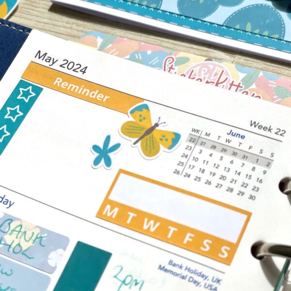 Close up of yellow butterfly and blue flower stickers on a planner page