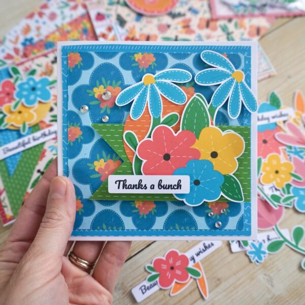 Bright and colourful Bold Floral handmade card with blue patterned paper, pretty paper flower toppers and 'thanks a bunch' sentiment