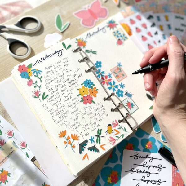 Open journal with text, decorated with flower and bug planner stickers